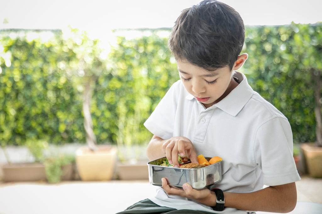 School kid is eating his lunch in stainless steel lunch box