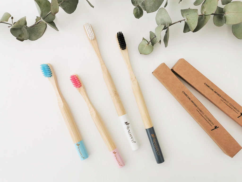 Bamboo toothbrushes charcoal, white, pink and blue in cardboard packaging boxes